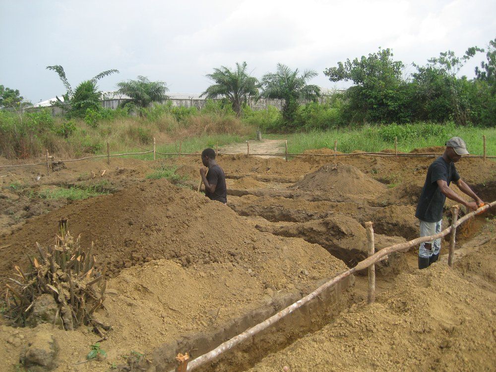 Two men are digging in the dirt in a field