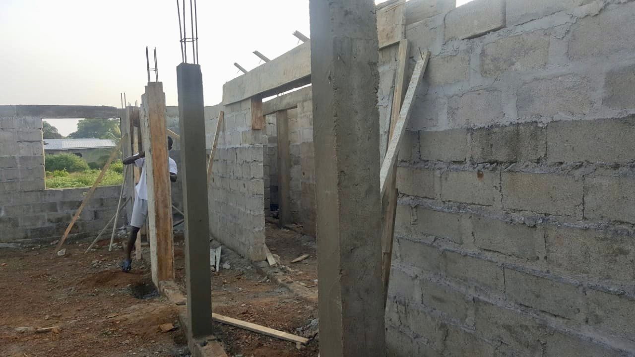 A man is standing in front of a brick wall under construction.