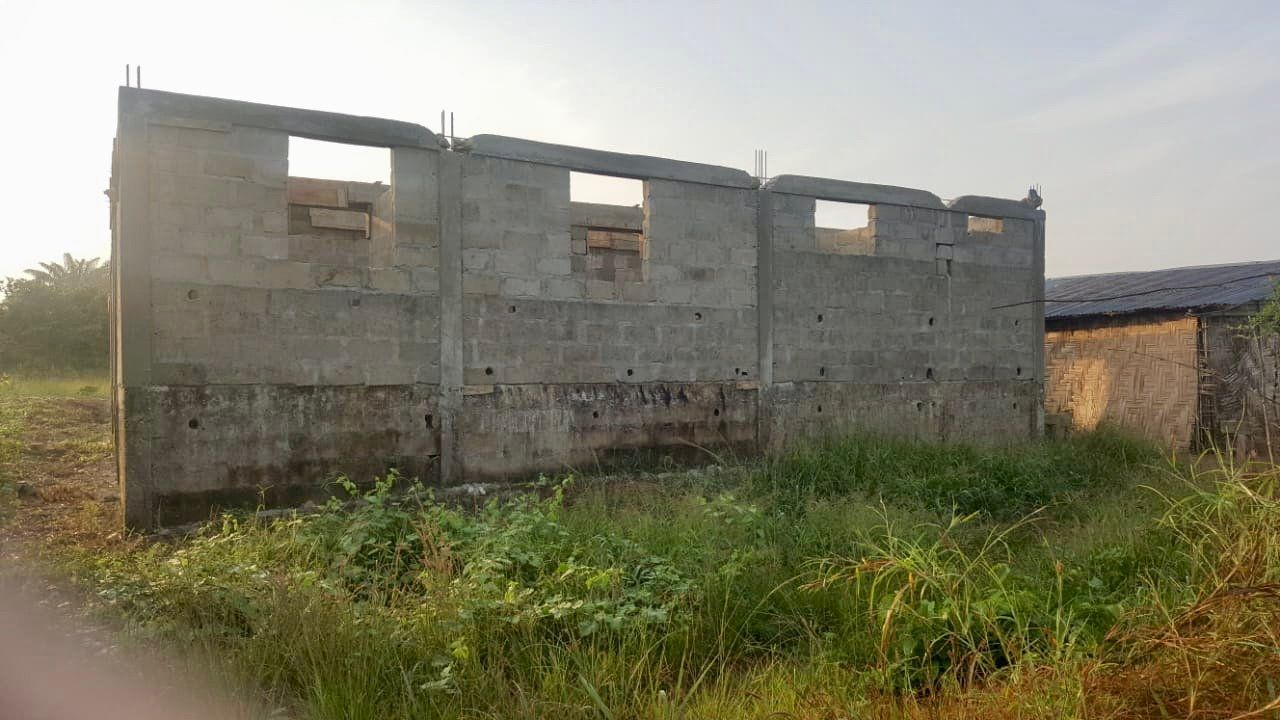 A concrete building is sitting in the middle of a grassy field.