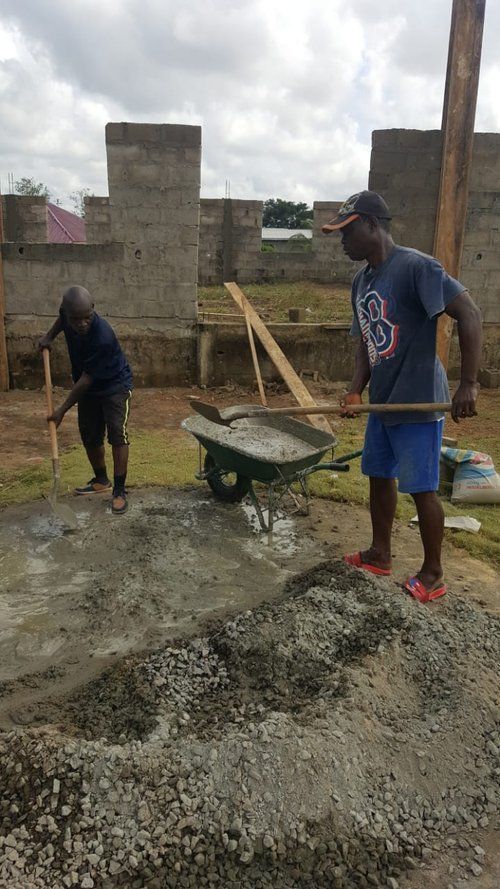 Two men are working on a construction site with shovels and a wheelbarrow.