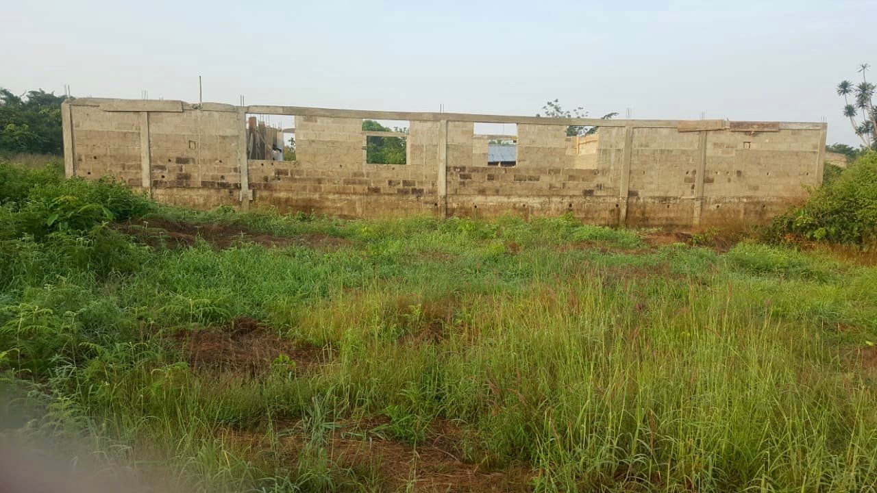 A brick building is sitting in the middle of a grassy field.