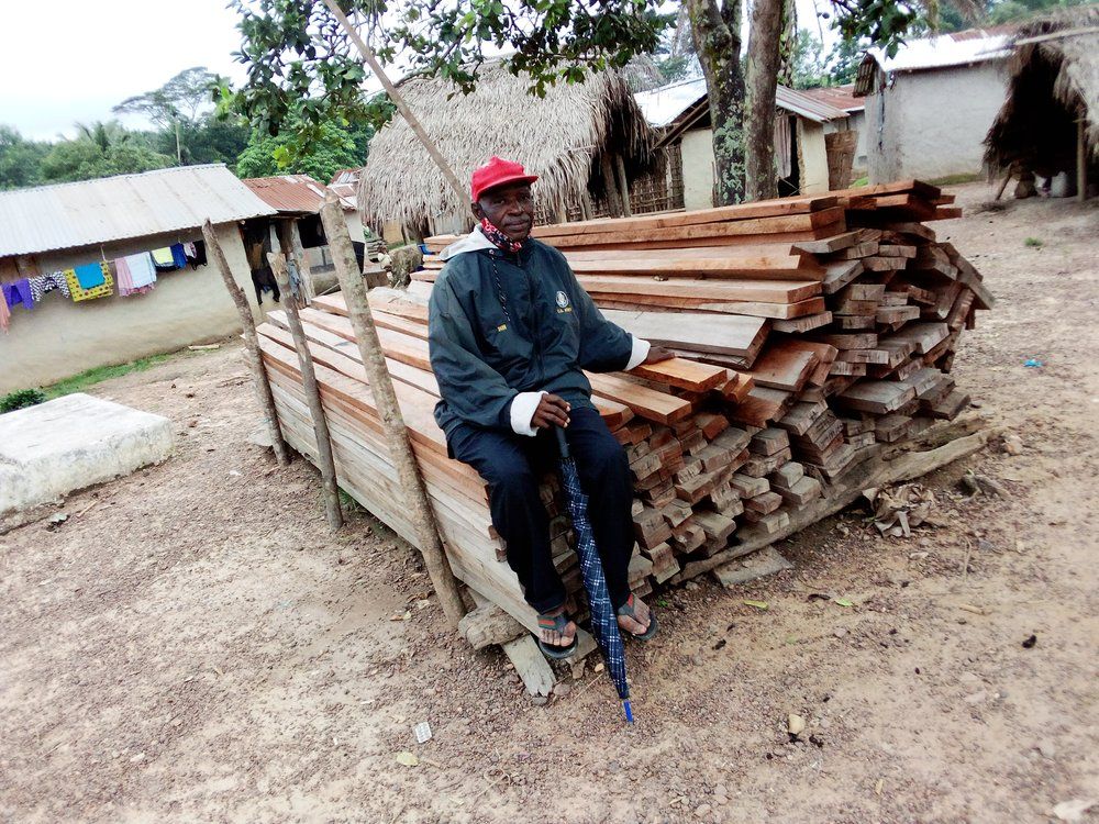 A man in a red hat is sitting on a pile of wood