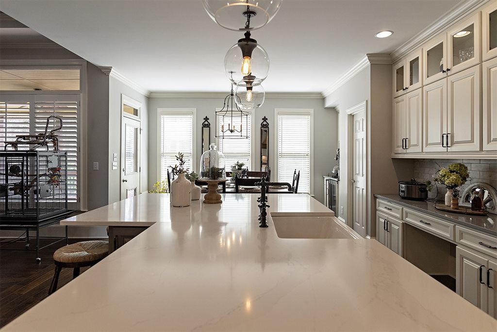 Spacious kitchen with large island, white cabinets, dark hardware, and light fixtures.