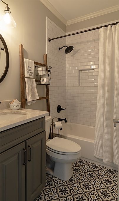 Bathroom with grey vanity, white subway tile shower, and patterned floor tile.