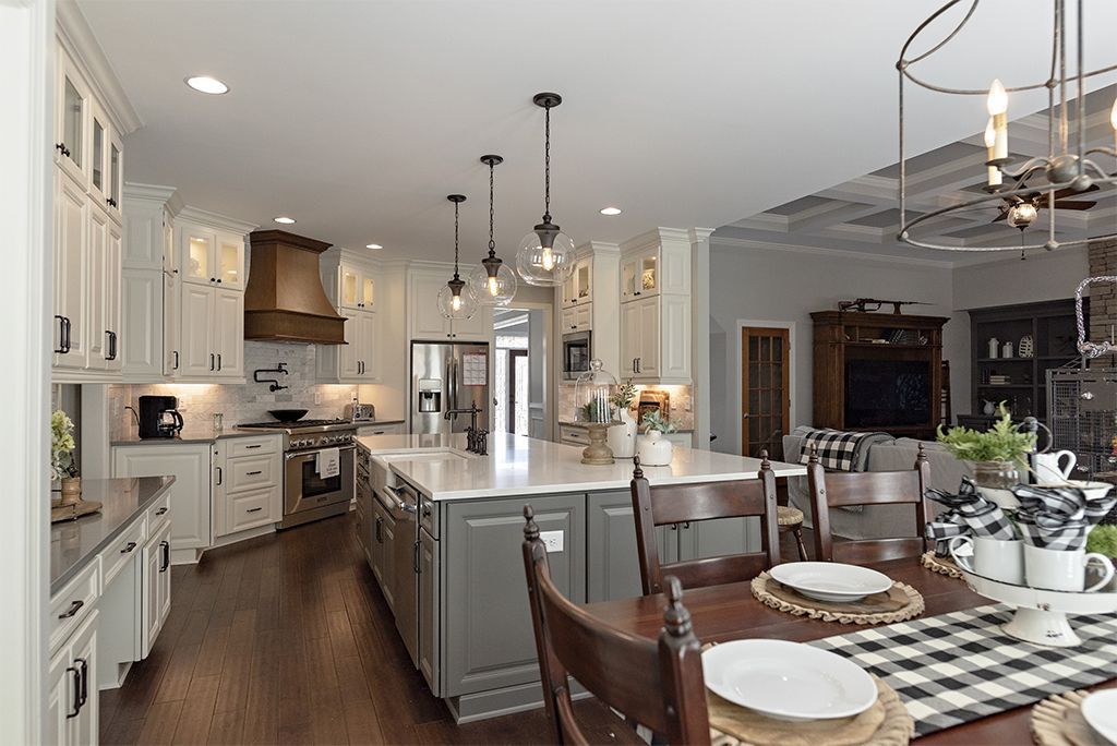 Elegant kitchen with white cabinets, gray island, and dark wood accents.