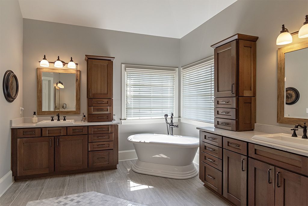 Bathroom with dark wood cabinets, a free-standing tub, and a window with blinds.
