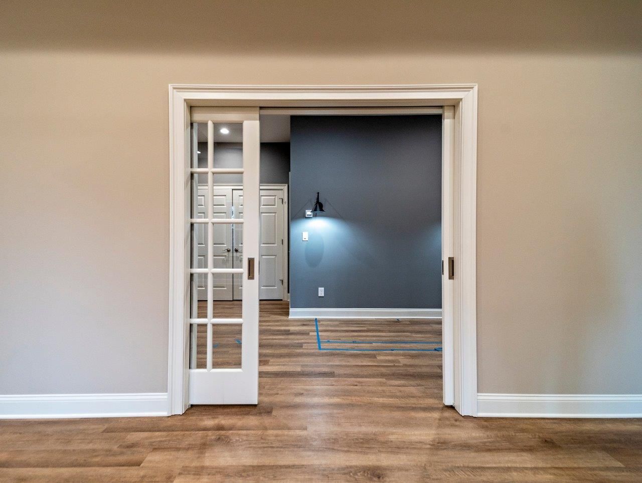 Interior doorway with open sliding glass-panel door, leading to a room with dark blue walls and hardwood floors