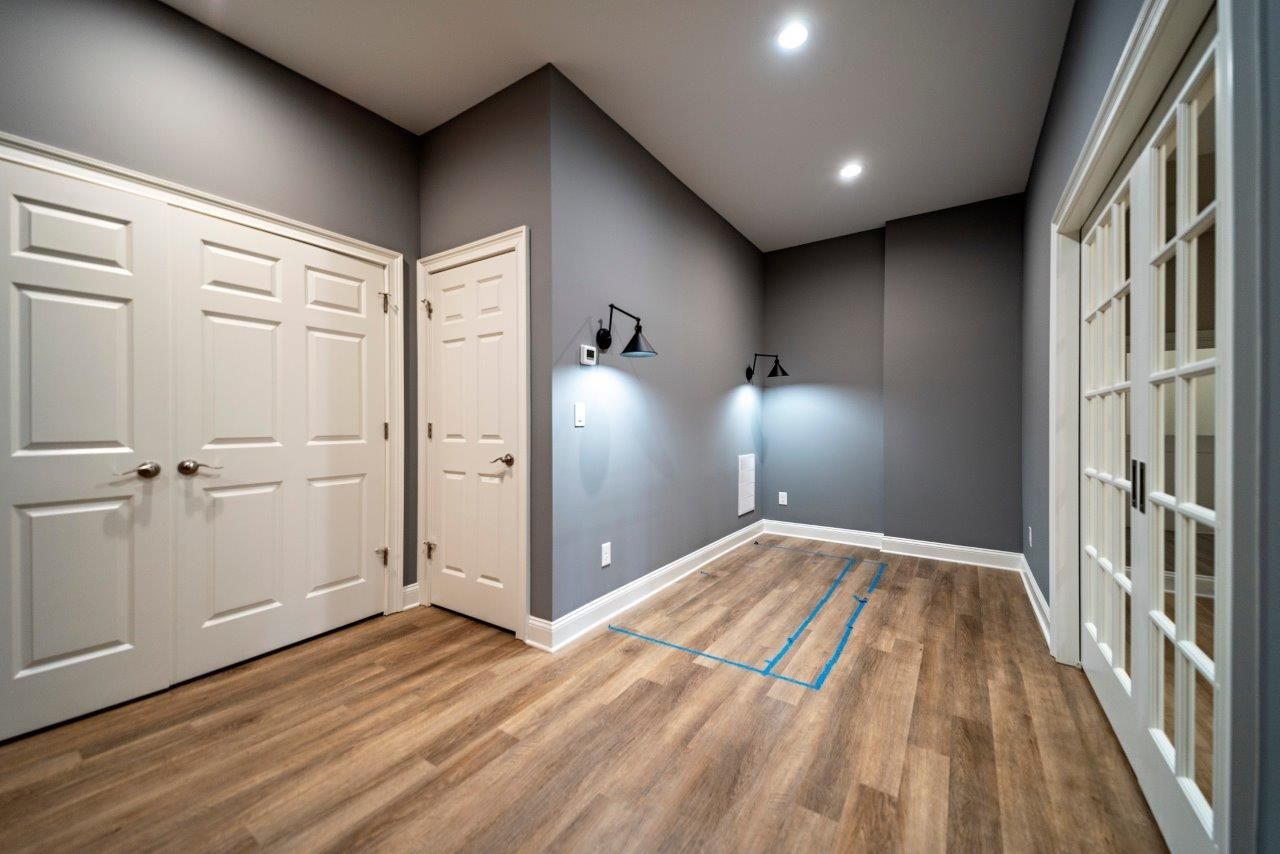 Empty room with wood floors, gray walls, white doors, and recessed lighting.