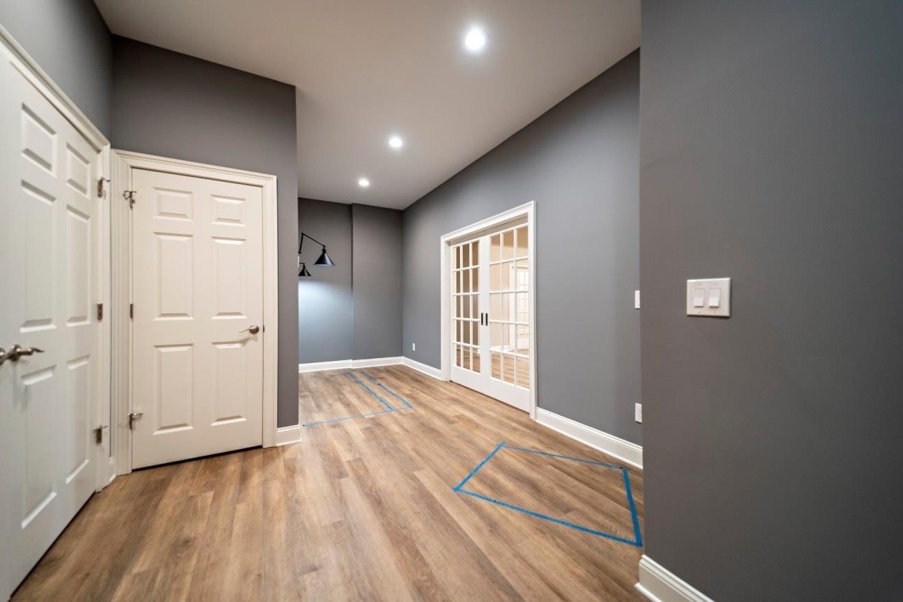 Interior room with wood flooring, grey walls, white doors, and glass French doors.