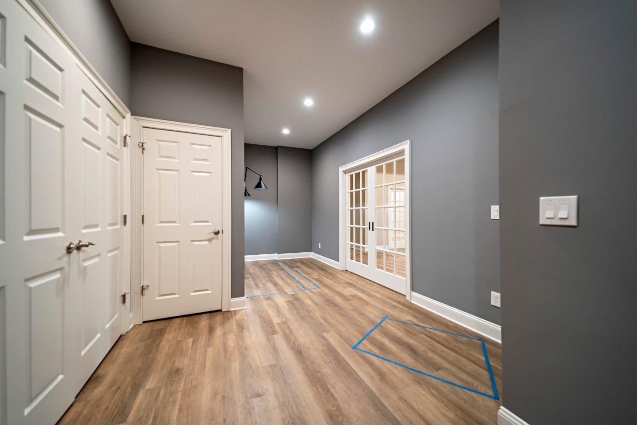 Empty room with gray walls, white doors, and light wood flooring.