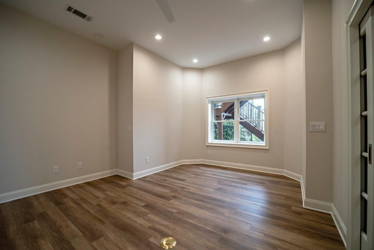 Empty room with wood floors, a window, and recessed lighting.