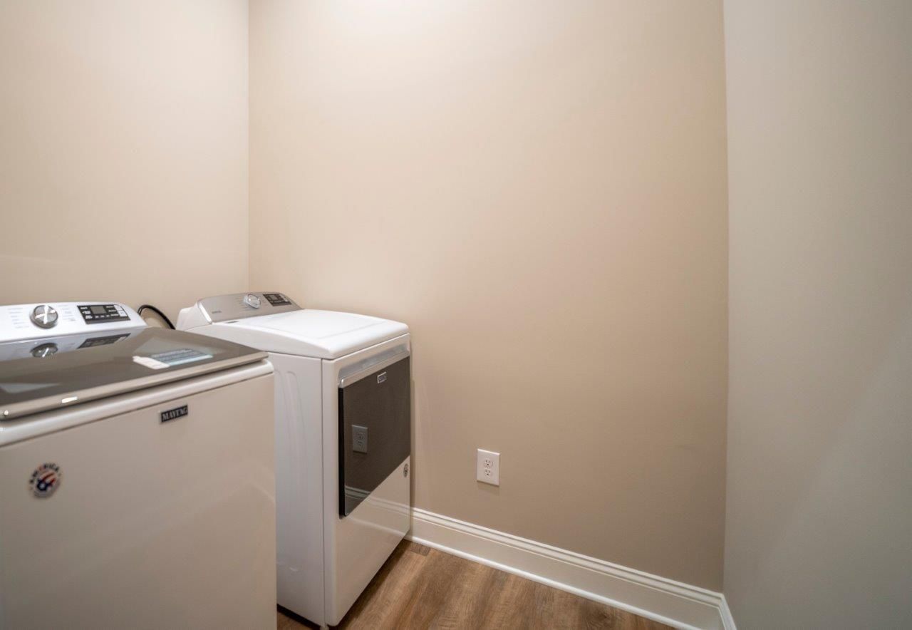 Laundry room with a white washing machine and dryer against a beige wall.