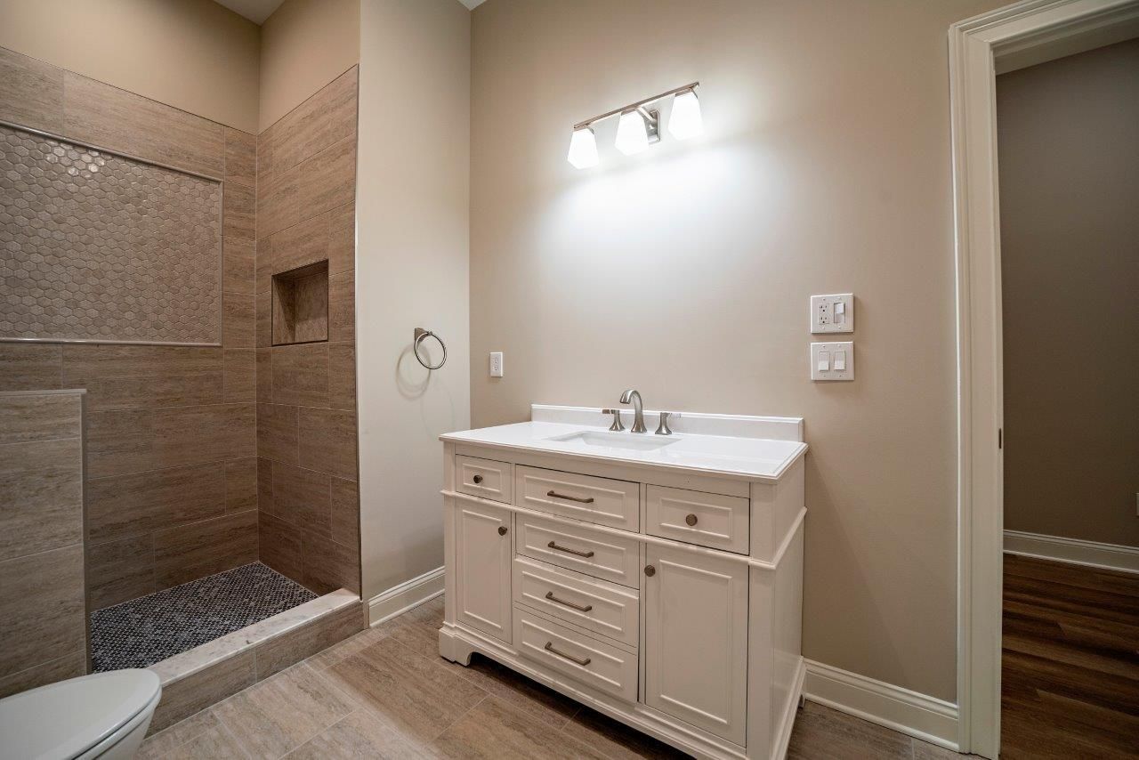 Bathroom with white vanity, shower, and tan walls.