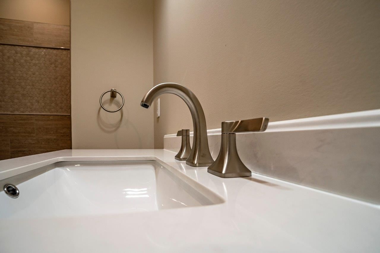 Bathroom sink with brushed nickel faucet, towel ring, and white countertop.