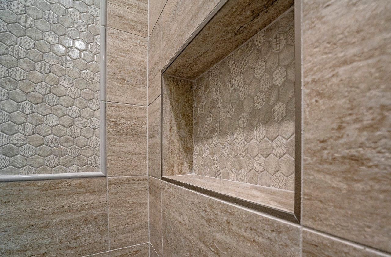 Tile shower with built-in shelf and honeycomb tile accents. Neutral brown tones.