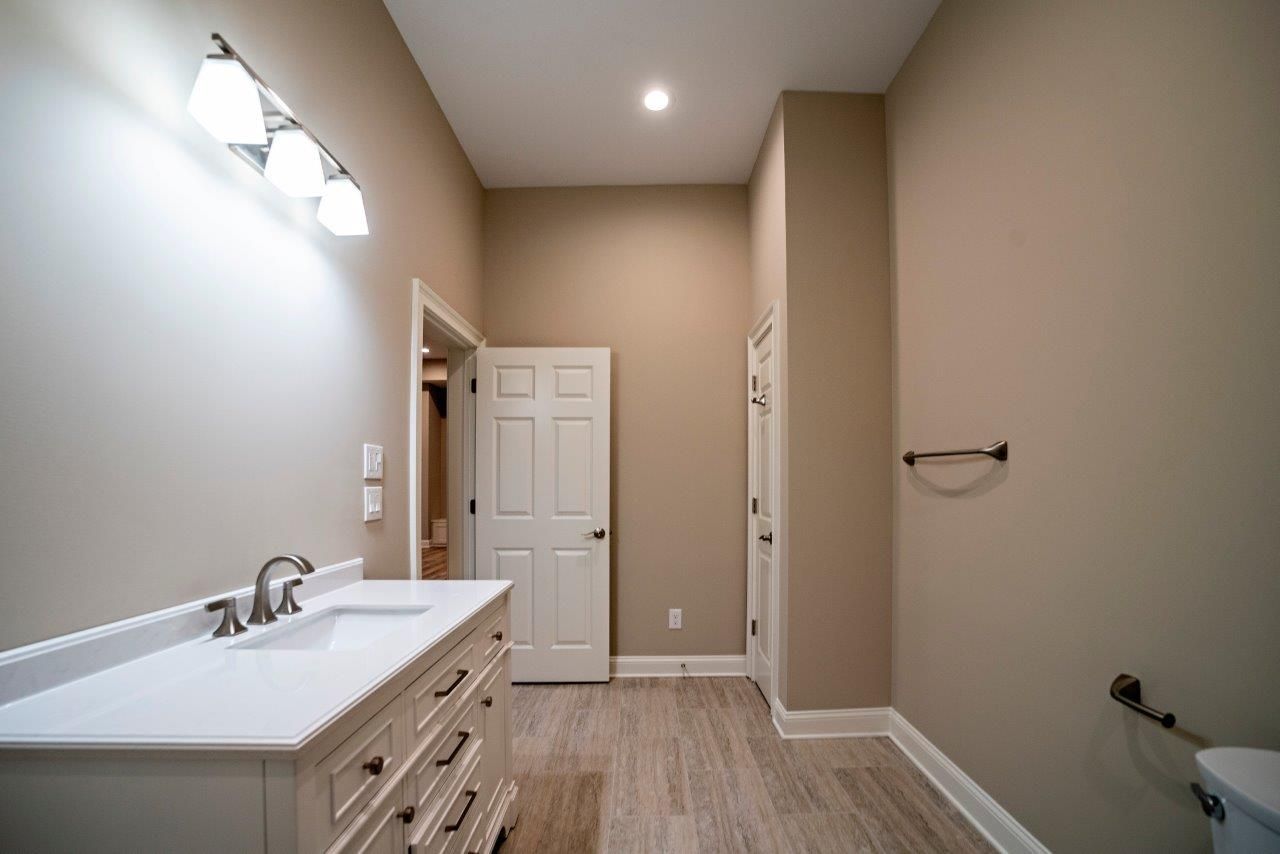 Bathroom with a white vanity, tan walls, and a closed white door.
