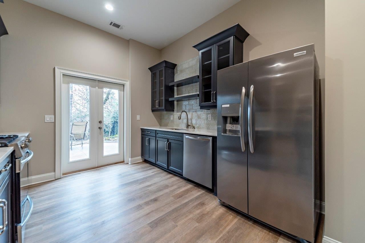 Kitchen with black cabinets, stainless steel appliances, and French doors to a backyard.