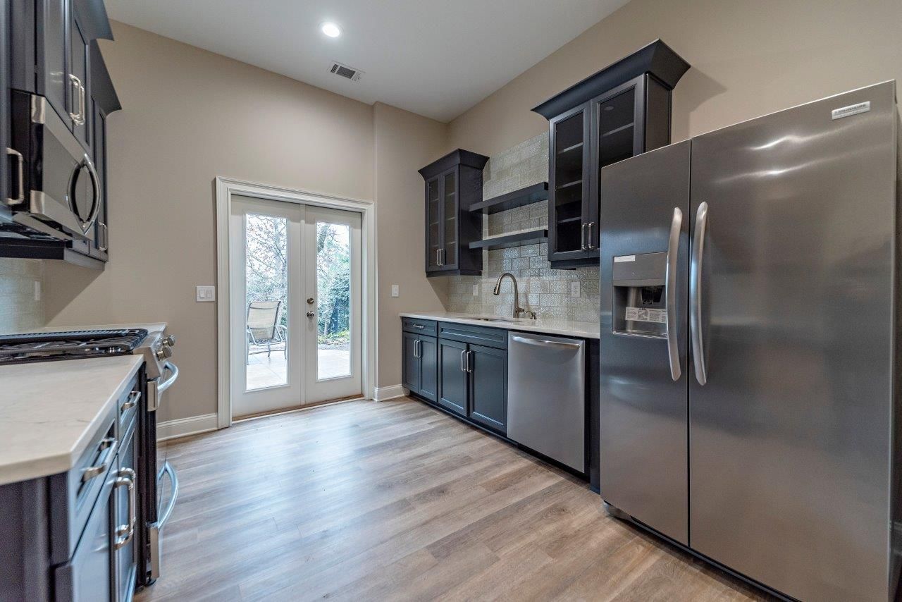 Kitchen with dark cabinets, stainless steel appliances, and French doors.