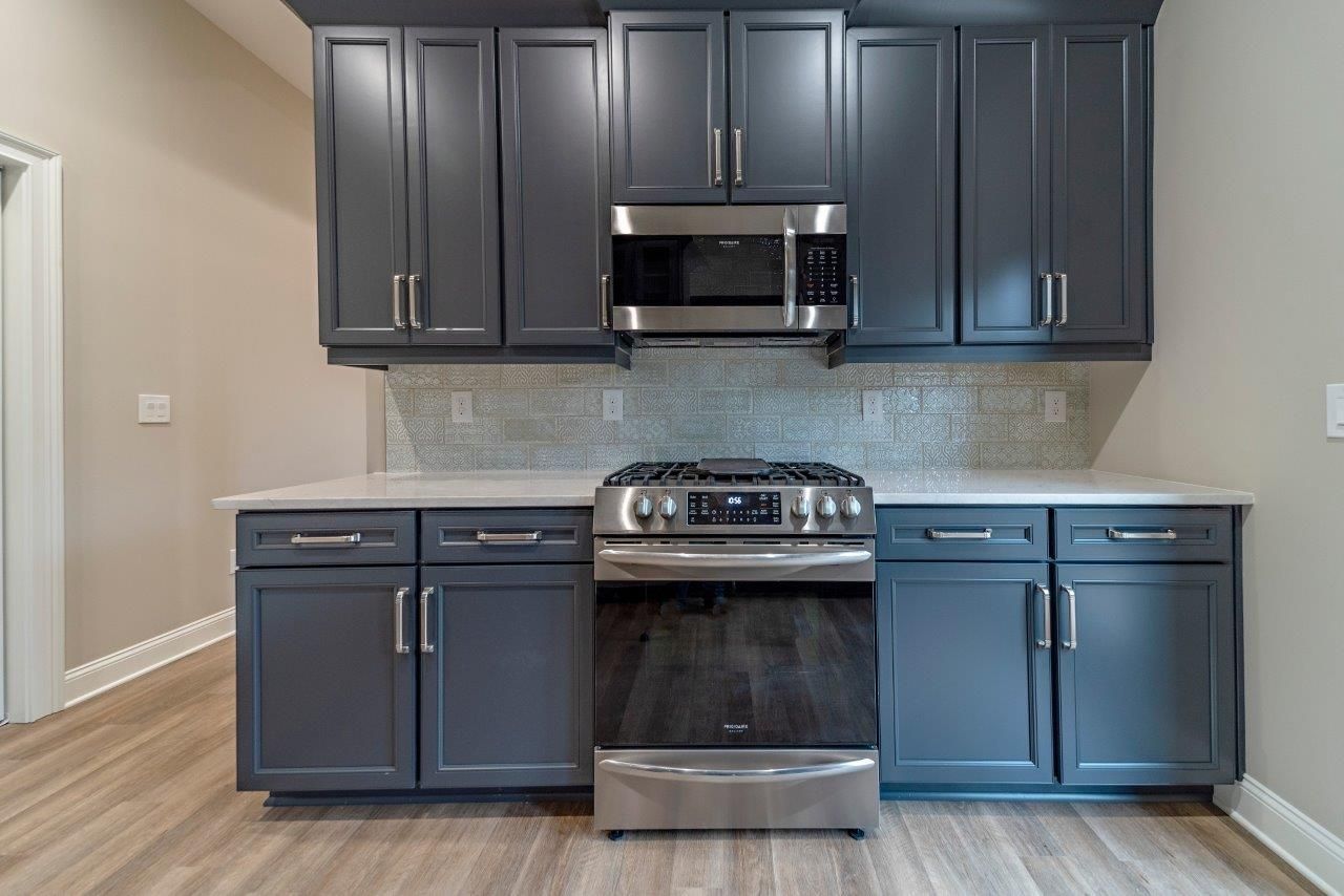Gray kitchen cabinets with stainless steel appliances and light gray countertops.
