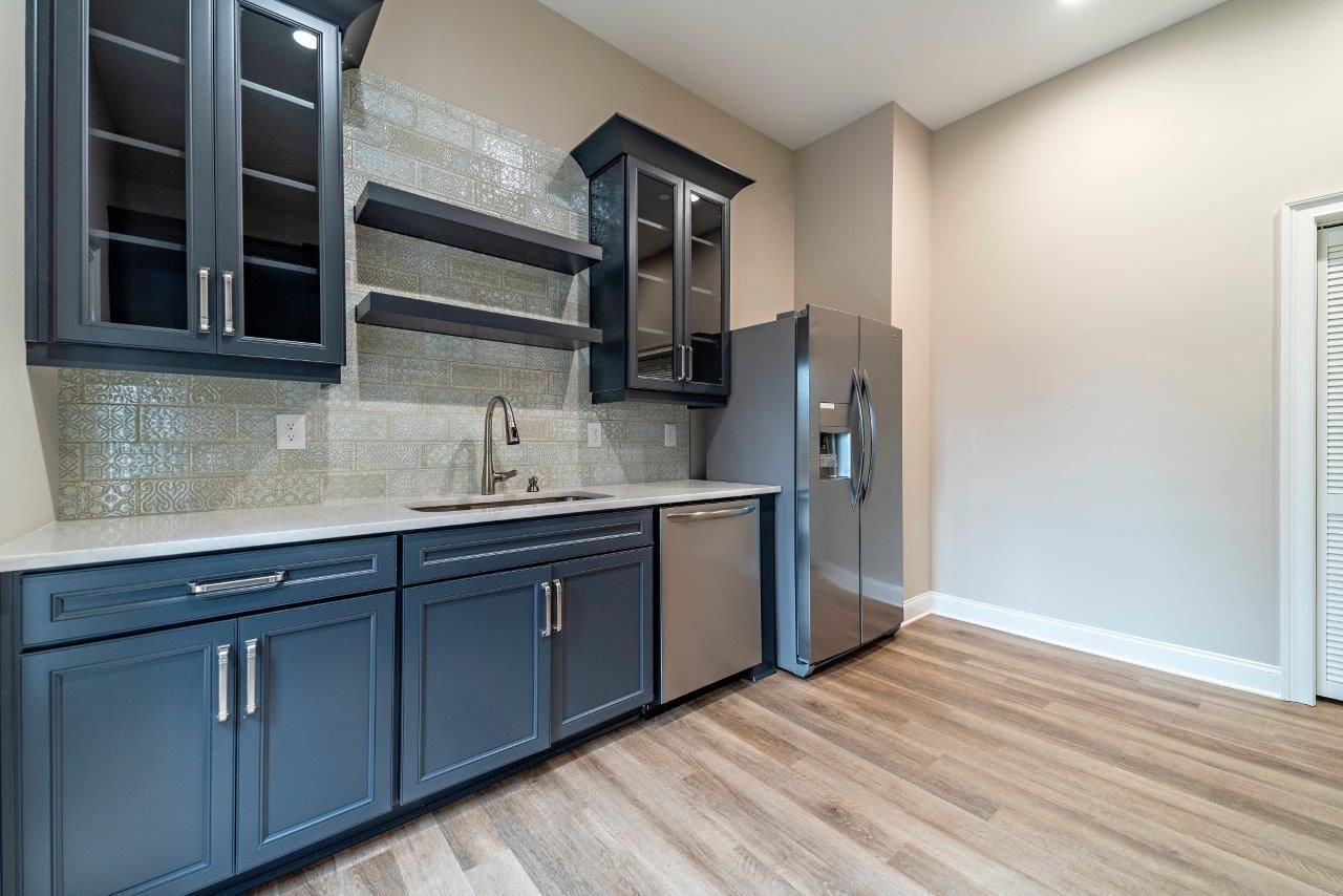 A small kitchen with gray cabinets, stainless steel appliances, and wood floors.