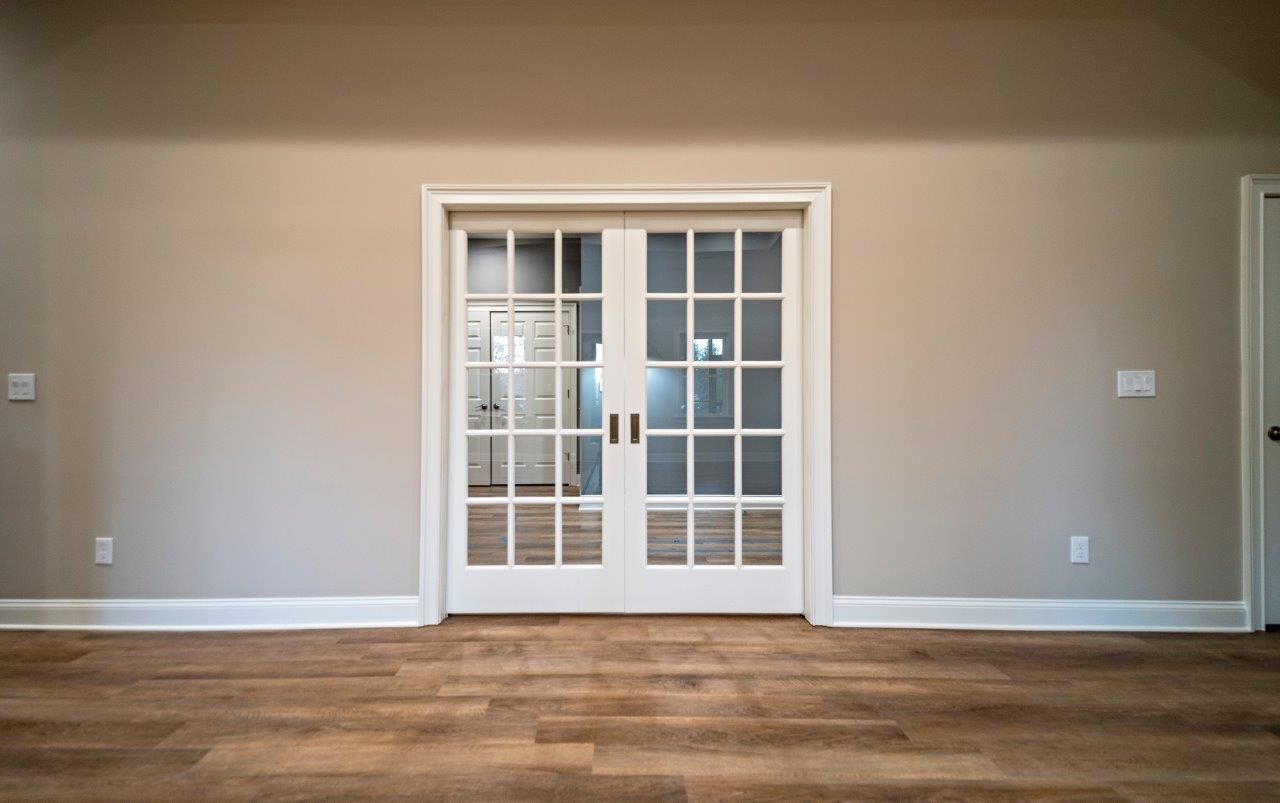 White French doors in a beige room with hardwood floors.