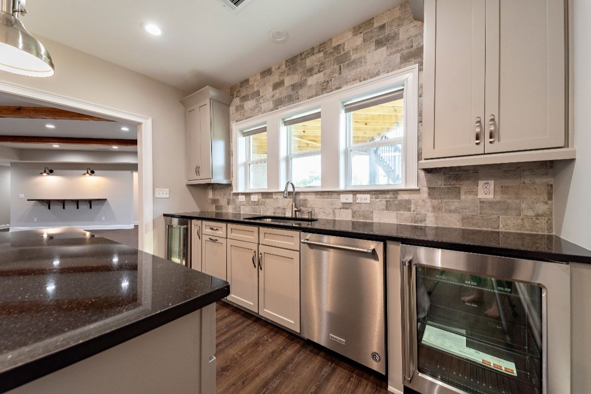Modern kitchen with gray cabinets, stainless steel appliances, and stone tile backsplash.