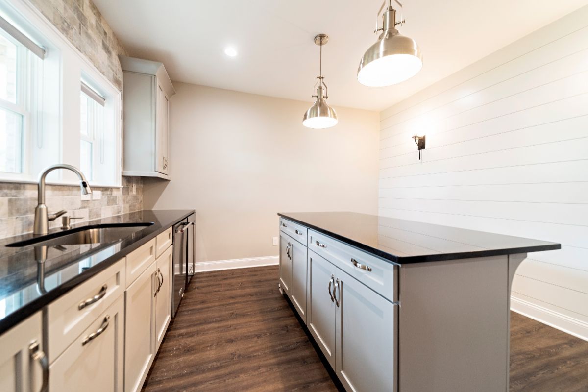 Modern kitchen with white cabinets, dark countertops, and an island.