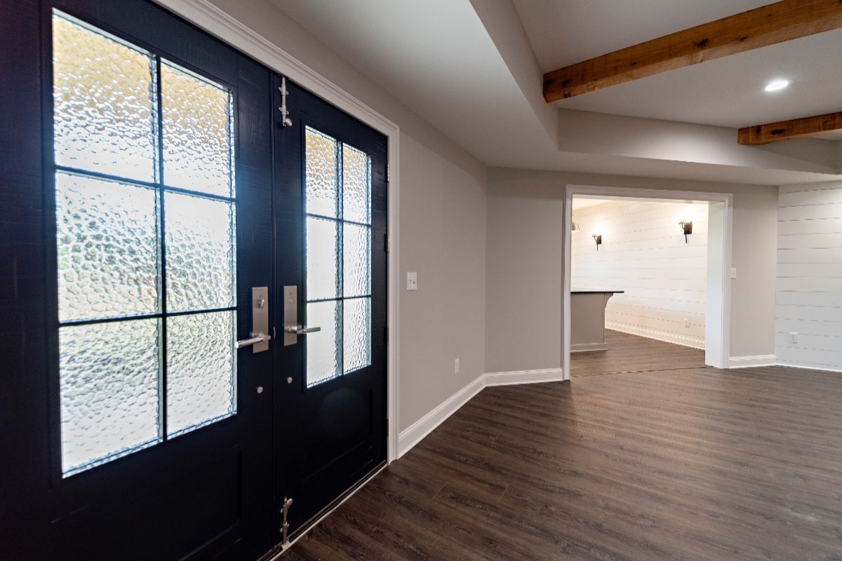 Black double doors with glass panes, wood floors, and neutral walls.