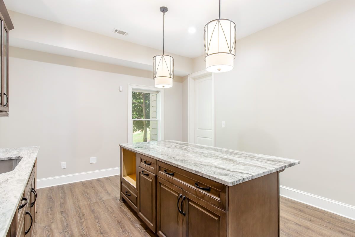 Kitchen with wood cabinets, island, granite countertop, and pendant lights.