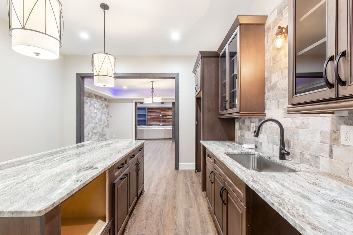 Modern kitchen with granite countertops, dark cabinets, and stainless steel sink.