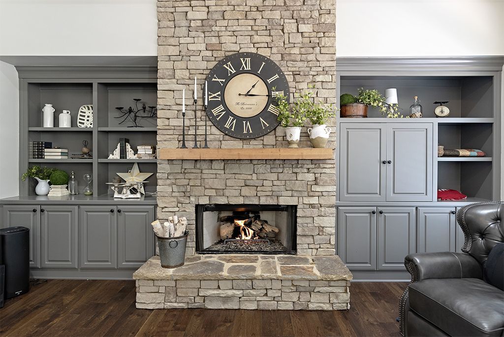 Stone fireplace with a wooden mantle and built-in gray shelves. A clock hangs above the fireplace.