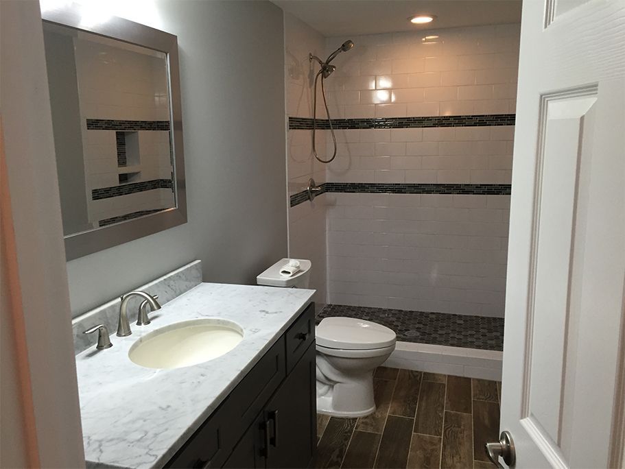 Bathroom with gray vanity, white walls, and a walk-in shower.