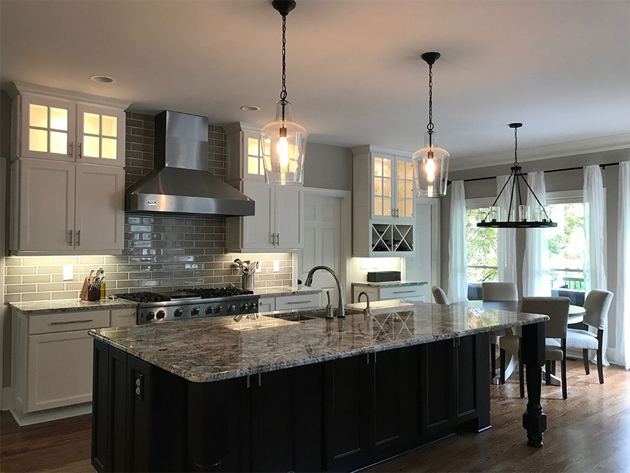 Modern kitchen with a black island, granite countertop, and light-colored cabinets.