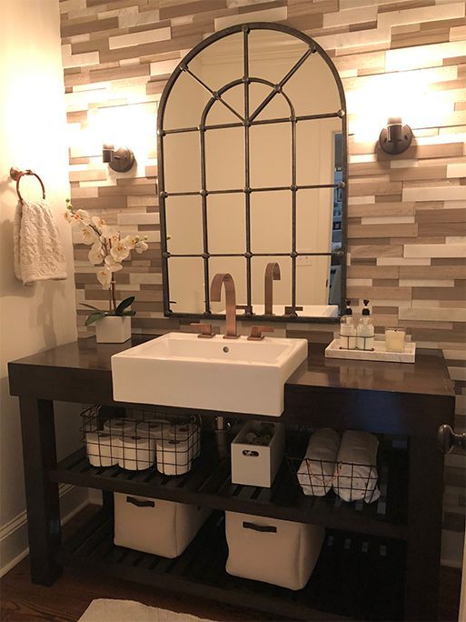 Bathroom with a large arched mirror over a white sink and dark wooden vanity.