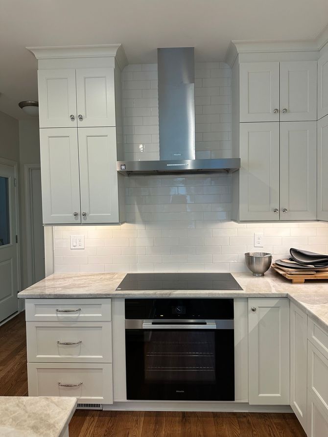 Kitchen with ornate beige cabinets, a range hood, and a granite countertop.