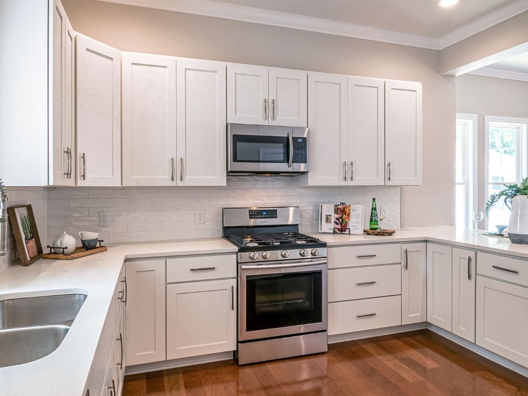 White kitchen with stainless steel appliances, white cabinets, and wooden floors.
