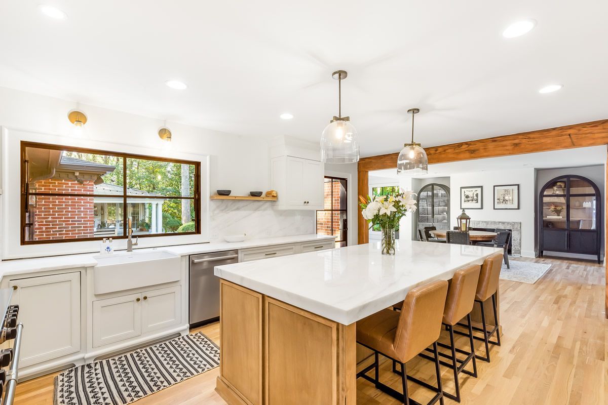 Bright kitchen with large island, white countertops, wood accents, and light wood flooring.