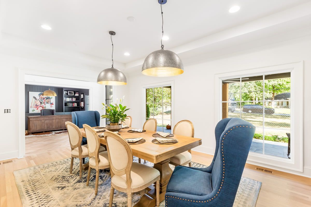 Dining room with wooden table, blue chairs, neutral rug, and two pendant lights.