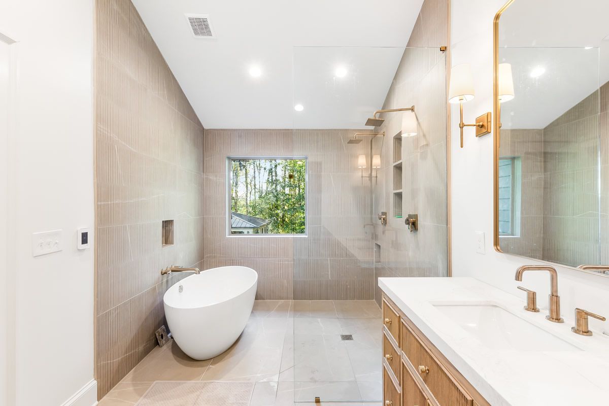 Modern bathroom with freestanding tub, tiled walls, vanity, and large mirror.