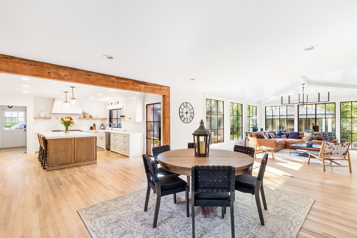 Open-concept kitchen and living area with a round dining table and a view through large windows.