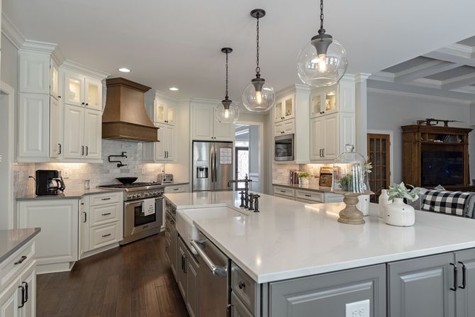 Spacious kitchen with white cabinets, large island, stainless steel appliances, and dark wood floors.