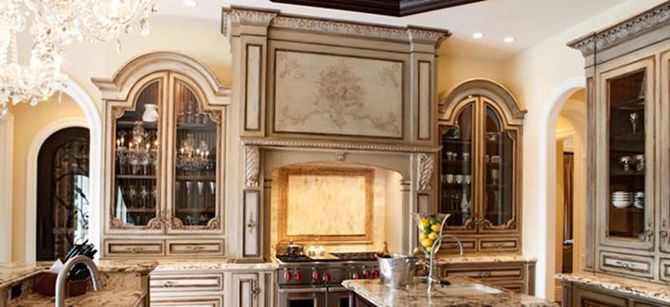 Kitchen with ornate beige cabinets, a range hood, and a granite countertop.