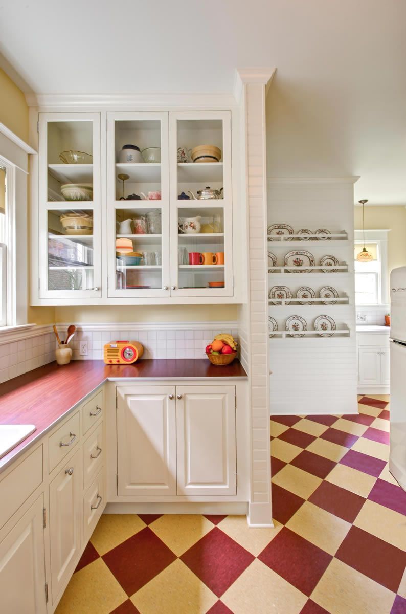 Kitchen with white cabinets, red countertop, and a checkered red and yellow floor.