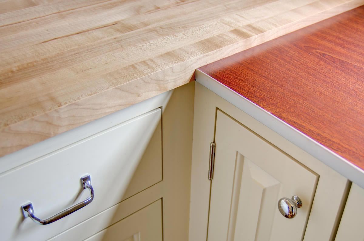 Butcher block and reddish-brown wood countertops on light-colored cabinets.