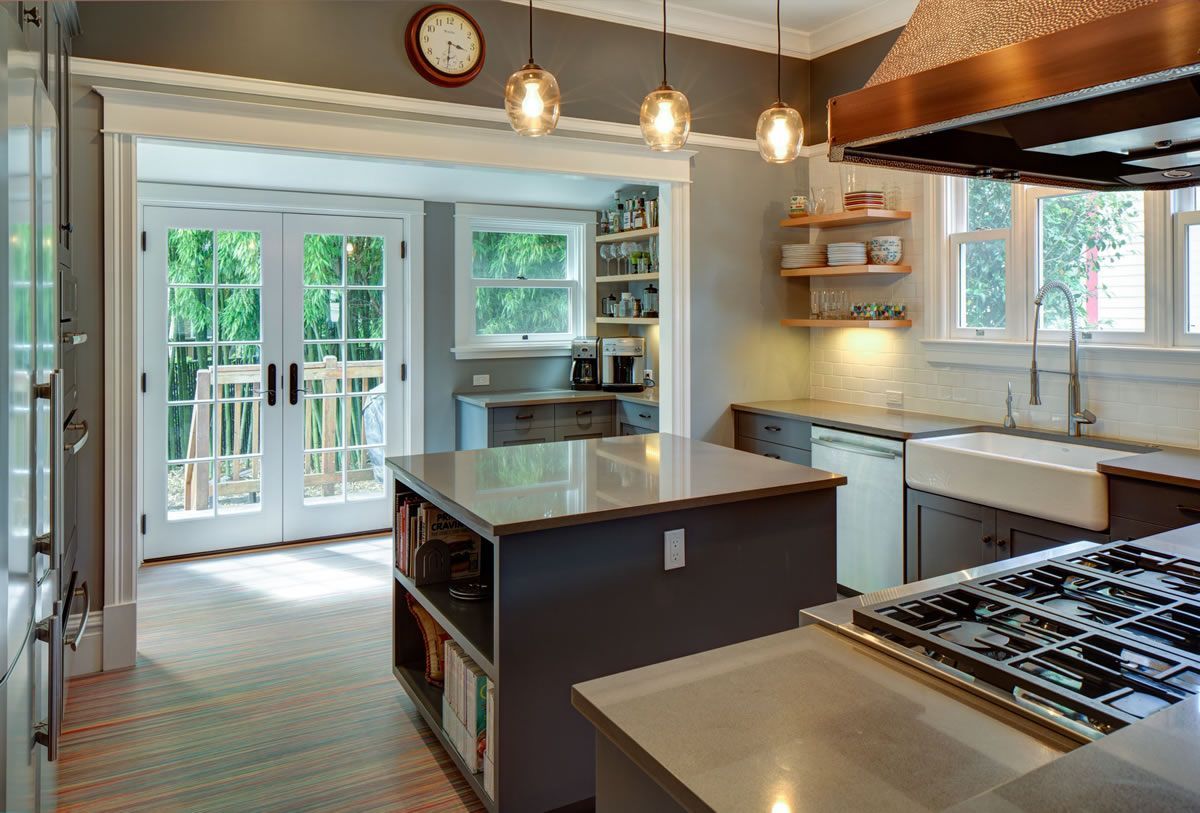 Kitchen with gray cabinetry, a central island, and French doors leading to a deck.