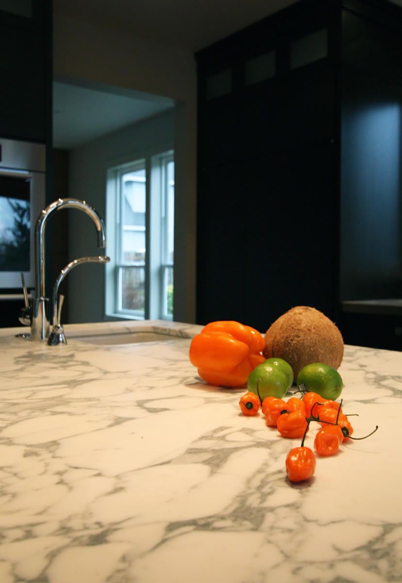 Close-up of a kitchen countertop with assorted produce: orange pepper, melon, limes, and red chilies.