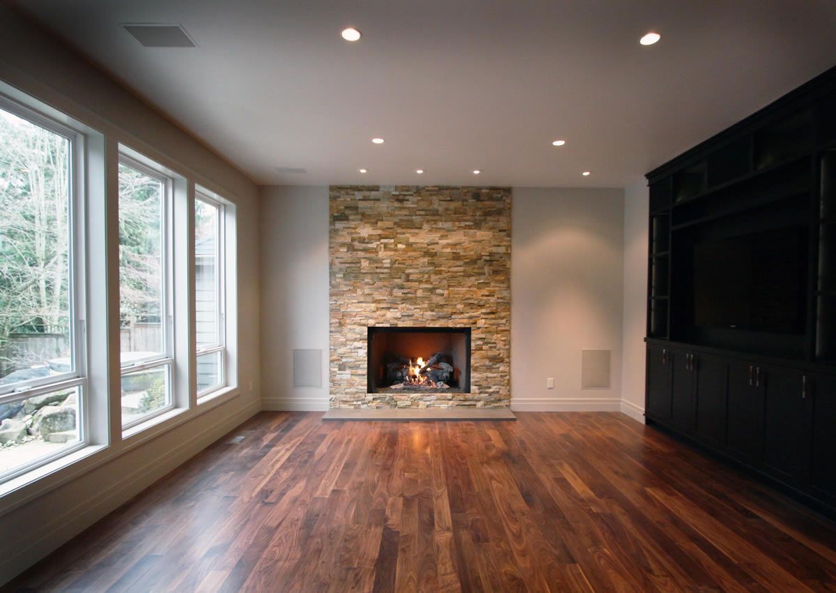 Empty room with fireplace and large windows, hardwood floors, and built-in entertainment system.