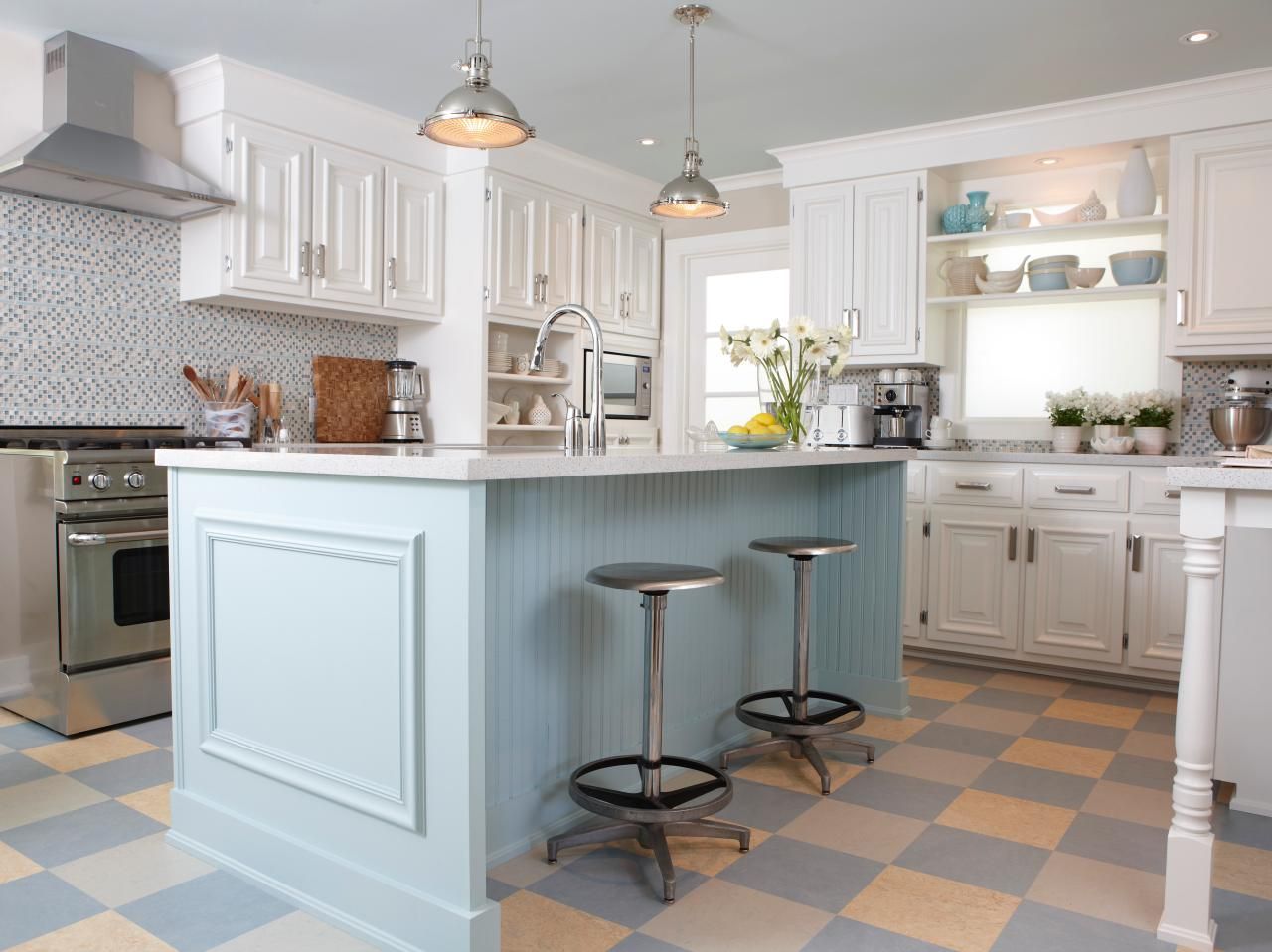 Kitchen with light blue and white color scheme. Island with stools, checkered floor, white cabinets.