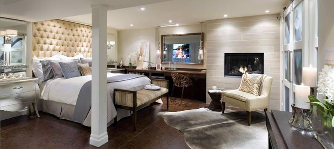 Luxurious bedroom with bed, fireplace, vanity, and seating, in neutral tones.