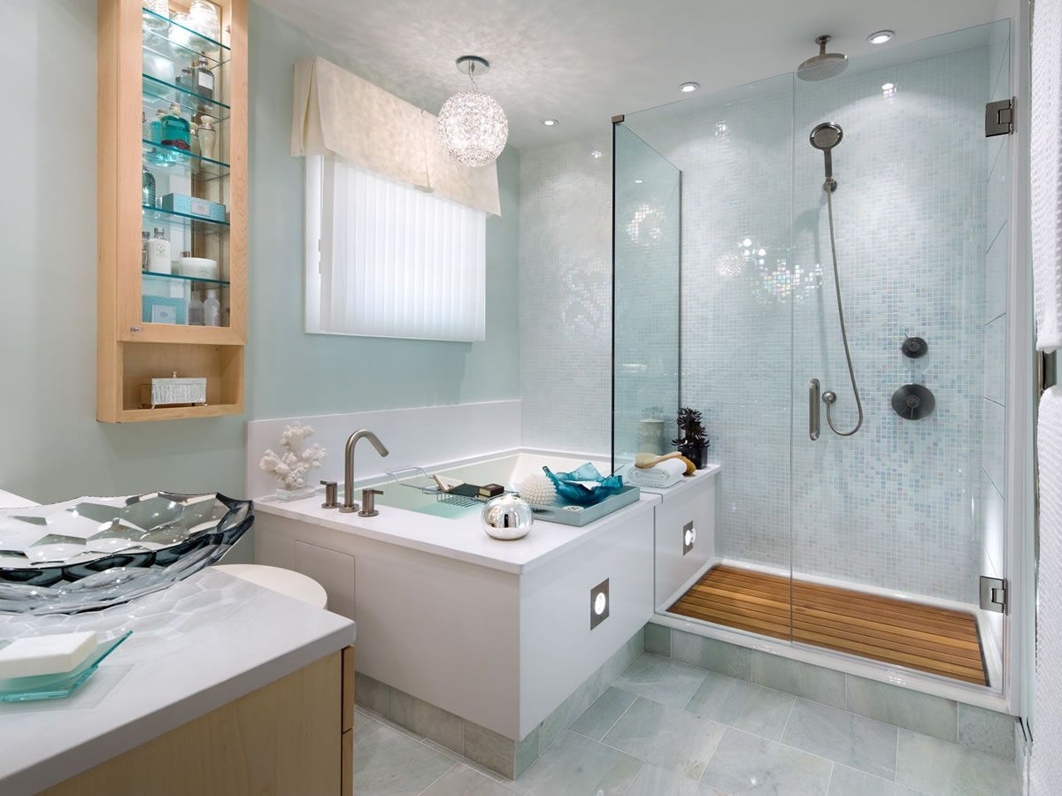 Modern bathroom with a bathtub, shower, light blue walls, and built-in storage.